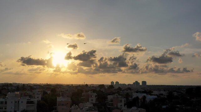aerial view of two Israeli Air Force attack helicopters flying over the Haifa city skyline during a golden sunset