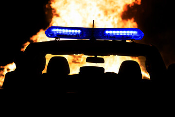 firefighter or policeman near your vehicle with emergency strobe lights in silhouette  watching...