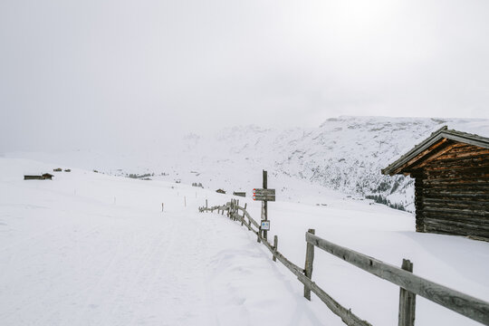 Holzh&uuml;tten auf der Seiser Alm mit Nebel und Wolken im Winter