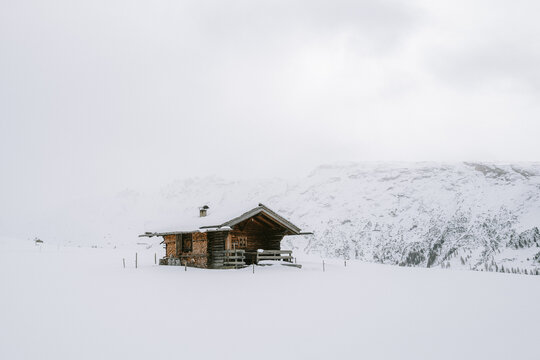 Holzh&uuml;tten auf der Seiser Alm mit Nebel und Wolken im Winter