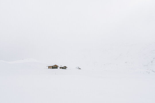 Holzh&uuml;tten auf der Seiser Alm mit Nebel und Wolken im Winter