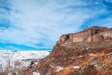 Fototapeta premium The scenic view of Kars, the Castle of Kars (Kars Kalesi), and the Holy Apostles Church in winter on a snowy day, in Turkey. 