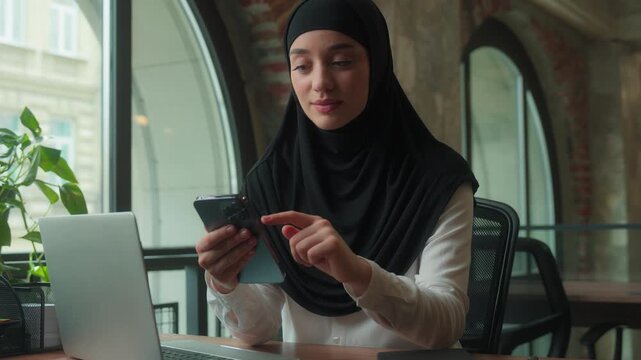 Muslim business woman in hijab scrolling mobile phone screen shopping online female islamic girl arabian businesswoman manager working in office using smartphone browsing social media gadget addicted