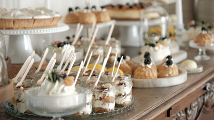 Elegant dessert buffet featuring assorted miniature pastries, cakes, and cream-filled glass jars on...