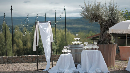 Naklejka premium Elegant outdoor wedding reception setup with a champagne tower on a wine barrel and scenic mountain views