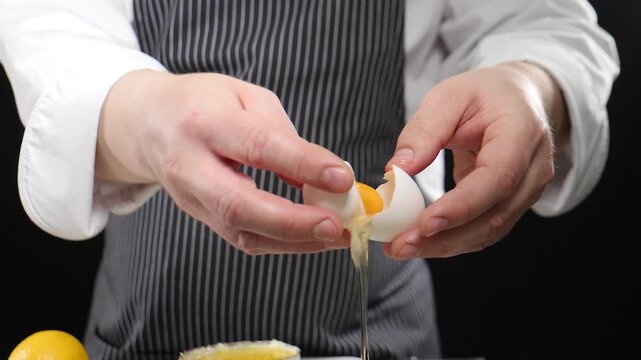 Chef cracking egg in bowl cooking food. Slow motion. Fresh white egg being cracked in yolk falls out of frame. 4 k video