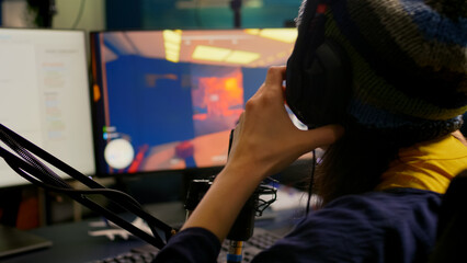 Close-up of streamer wearing professional gaming headphones and playing first person shooter video games. Player sitting in streaming studio using technology network wireless during online competition © DC Studio