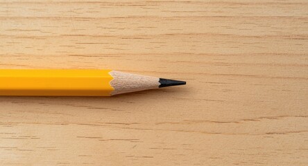 Obraz premium Detailed shot of a sharpened yellow pencil on a natural grain wood surface