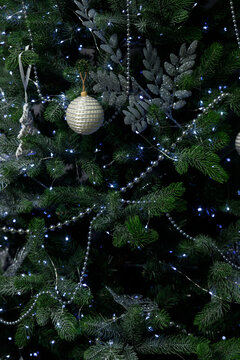 A decorated Christmas tree with silver ornaments and blue fairy lights glowing softly against dark green pine branches.