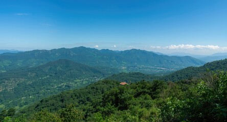 Naklejka premium Clear sky over majestic green mountain range featuring dense vegetation and peaceful scenery