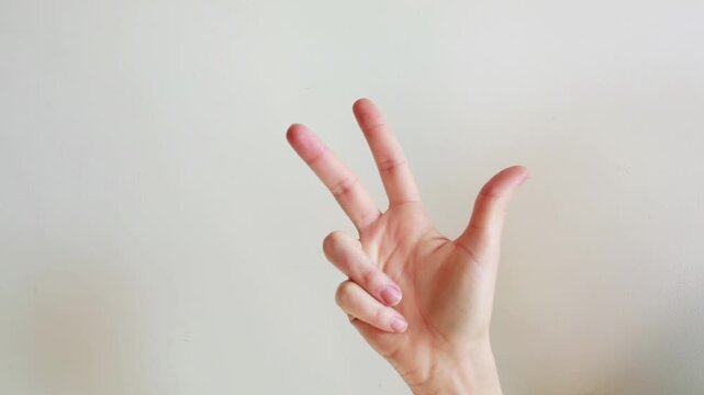 Female hand showing three fingers gesture isolated on white background. Human hand counting number three using fingers.