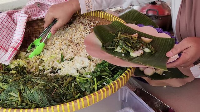 Freshly prepared pecel by street vendor, served on banana leaves. Authentic street food, serving pecel with fresh ingredients daily. Traditional Indonesian pecel with vegetables and fried tofu. 