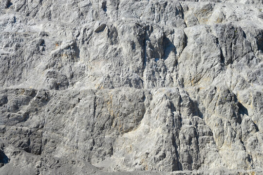 A close up view of a steep stone quarry face showing intricate rocky layers and rough textures of excavated limestone under bright daylight