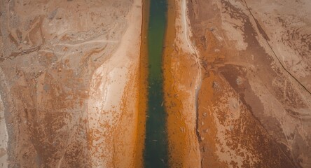 Obraz premium Birds eye view capturing a slender water stream surrounded by arid lake floor textures