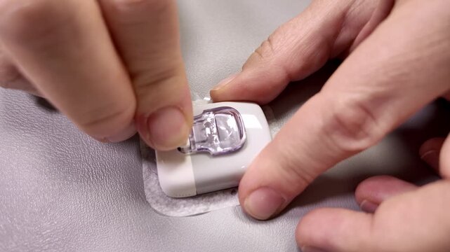 Close up of hands applying medical patch or sensor on skin, healthcare and self care concept
