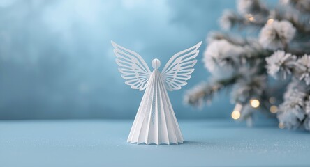 Naklejka premium Festive card concept with a delicate paper angel set before a serene blue background and snow-covered Christmas tree