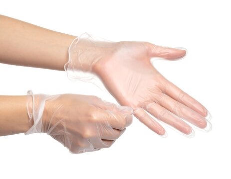Two hands wearing clear, disposable gloves against a white background. Hands are posed for a close inspection