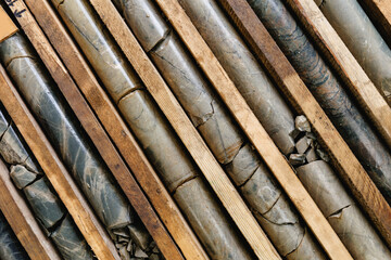 Fototapeta premium Geological rock core samples and wooden slabs arranged in diagonal, top view