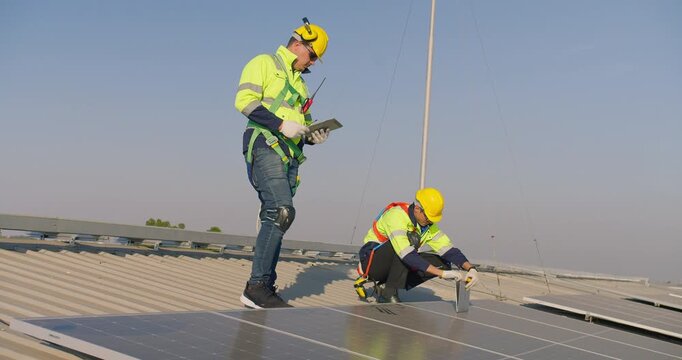 Professional industrial engineers are inspecting a rooftop solar panel array using digital technology, focusing on renewable energy optimization and strict industrial safety compliance.