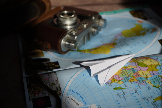 globe on the table, vintage photo camera on the world map, travel vibes, adventure spirit ideas, vacation season destination choice, active lifestyle, history and culture aesthetics, paper craft airpl