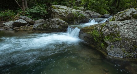 Obraz premium Close up of lively water rushing over boulders producing waterfalls in forest stream