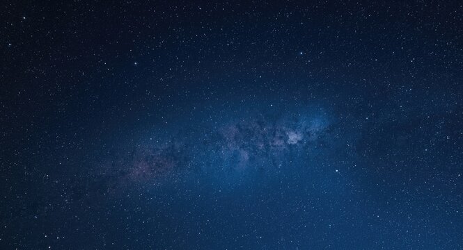 Blue tinted panorama of star filled universe with milky way and nebula in dark sky