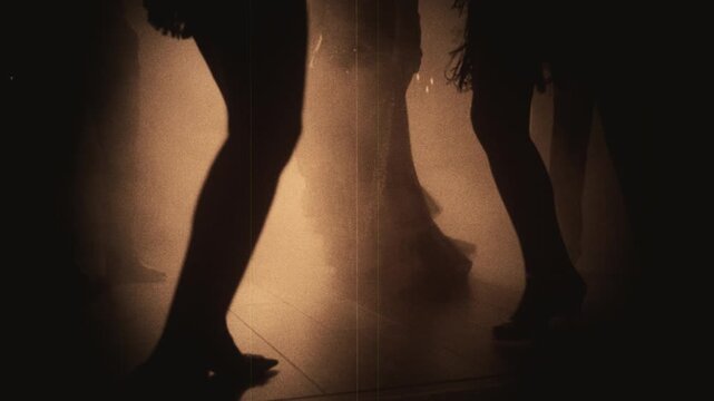 Old film 1920s style sepia color, group of people close-up body part legs feet shoes high heels dancing crowd in dark night out club. Women men flapper have fun joy at dance floor retro party rave 20s