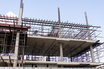 Concrete beams rise above scaffolding, forming a building's frame