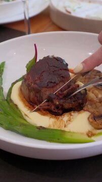 hands slicing freshly grilled juicy beef steak meat with a knife food close-up. High quality FullHD footage super slow motion