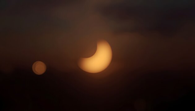 Ramadan new moon sighting soft golden glow crescent through dark cloudy sky with warm bokeh background
