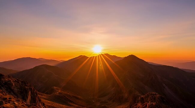 Spectacular mountain range silhouette under a vibrant sunrise with dramatic sunrays