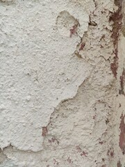 Fototapeta premium Detail of a chipped wall corner with white coating falling off to show red clay. For renovation ads, distressed art styles, and texture overlays.