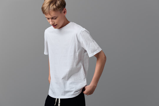 Man in white t shirt standing against a minimalist gray backdrop, casual wear vibe with a relaxed pose, simple studio setup and neutral tones for versatile everyday style