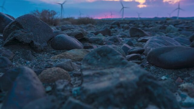 Rocky Desert Landscape with Wind Turbines at Dusk