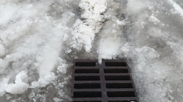 Cast iron drainage grate during snow melting in overcast day