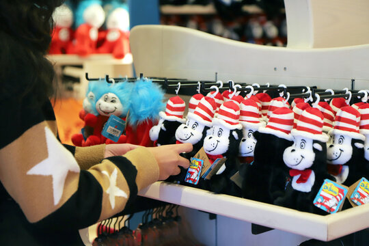 Person choosing Dr Seuss Cat in the Hat plush toys in souvenir shop retail display