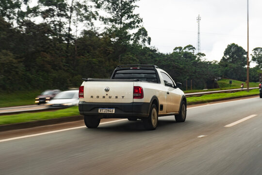 White Volkswagen Saveiro rear view, Compact pickup truck driving on a cloudy highway