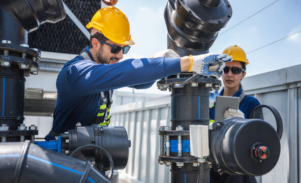 Professional maintenance engineers repairing industrial water pipe system with wrench, Technical team using digital tablet and tools for high-pressure piping inspection at site