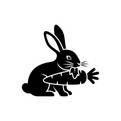 Fototapeta premium A black silhouette of a rabbit happily munching on a fresh orange carrot silhouette