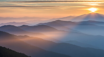 Fototapeta premium A breathtaking sunrise over a mountain range shrouded in mist, casting a warm glow across the peaks and valleys.