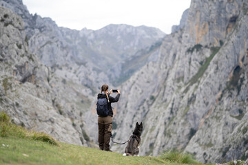Naklejka premium Woman hiking with dog photographing picos de europa mountains