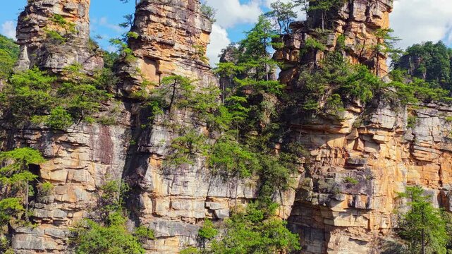 Majestic sandstone pillars and lush greenery in Zhangjiajie, Hunan, China, showcasing a unique quartz peak forest landform under clear blue sky.