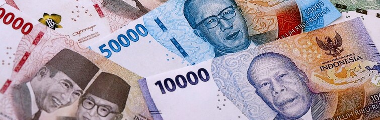 Indonesian rupiah money bills pile on table. Indonesia banknotes of IDR currency close up. © Larysa