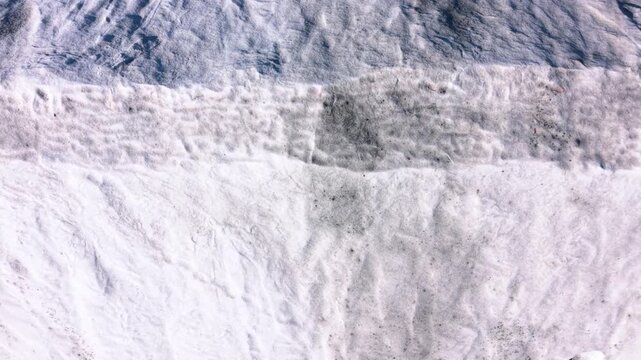 Snow blankets the park in winter. Snow blankets the ground in a park during winter. The landscape shows patterns and textures on the snow surface.