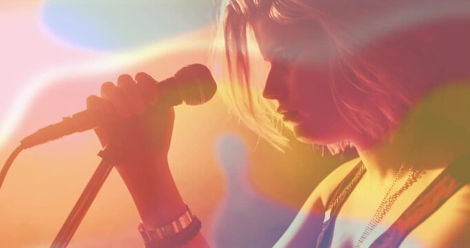 Vertical video: Woman singer tuning mic leaning singing performing music as flares revealing shadow