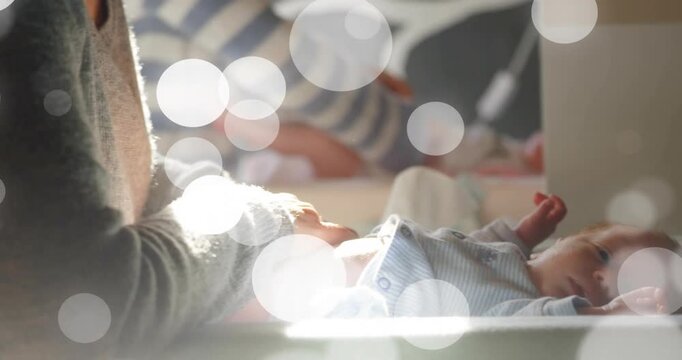 Mom leaning over infant at table starting nappy change tucking nappy for health calming under bokeh