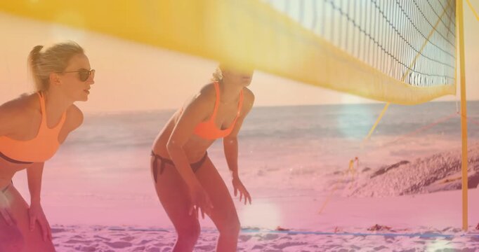 Two women stepping under net taking ready volleyball stance tracking offcourt play to receive ball