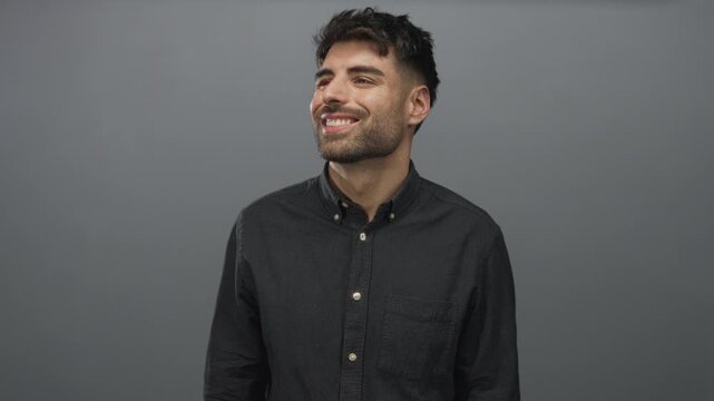 Man wearing casual buttondown shirt looking up and smiling against grey studio wall; optimism growth ambition.