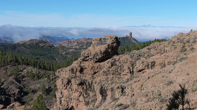 Majestic view of Roque Nublo and Teide volcano seen through the Ganifa rock arch, also known as La Ventana del Nublo in Gran Canaria