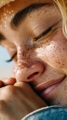 Naklejka premium Close-up of a woman with freckled skin and closed eyes, relaxing outdoors. She wears a straw hat and denim jacket, feeling the bright sun on her face during the day